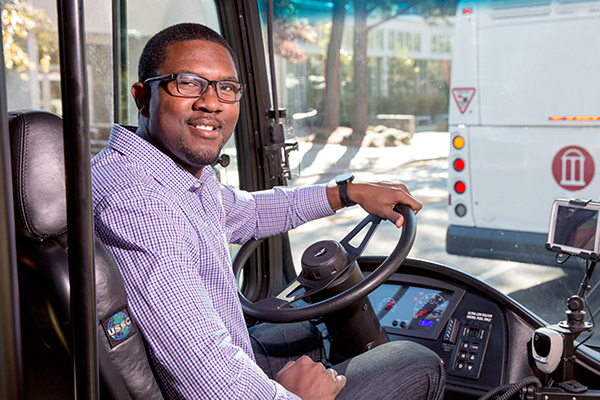 UGA Transportation employee sits in the driver's seat of a bus.