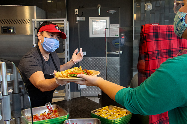 An team member hands a customer a burger and fries.