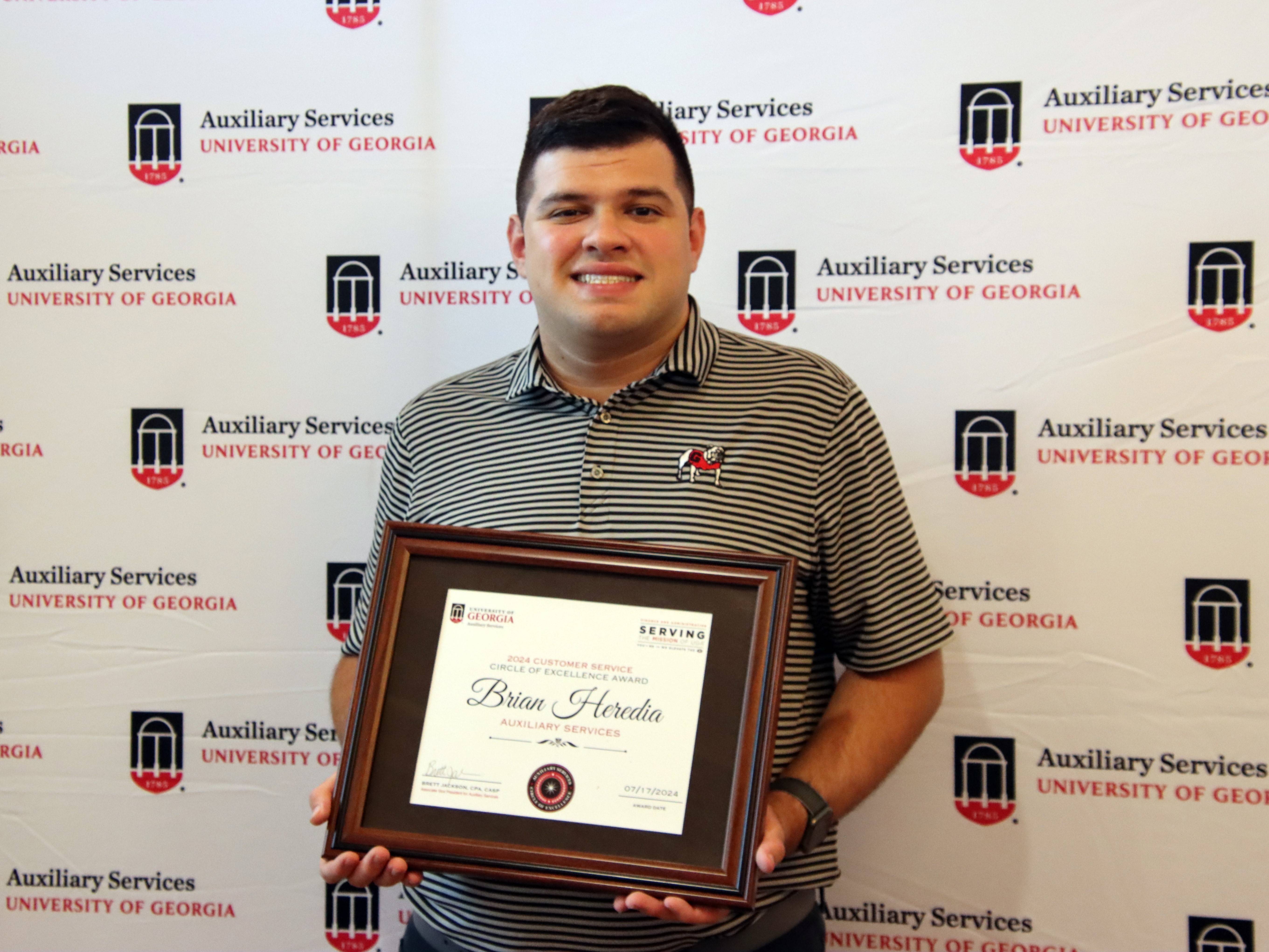 A photograph of a man holding a framed certificate.