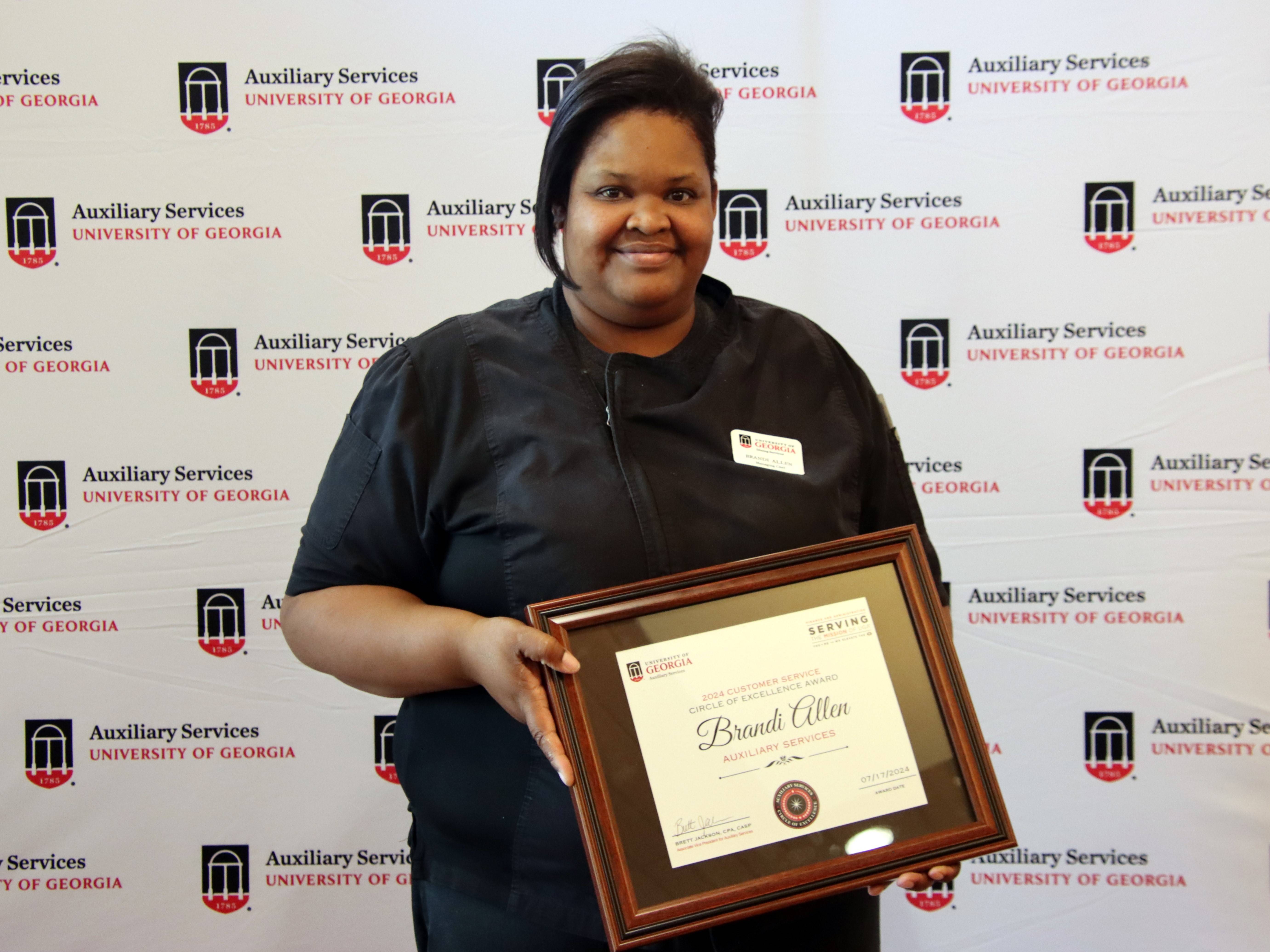 A photograph of a woman holding a framed certificate.