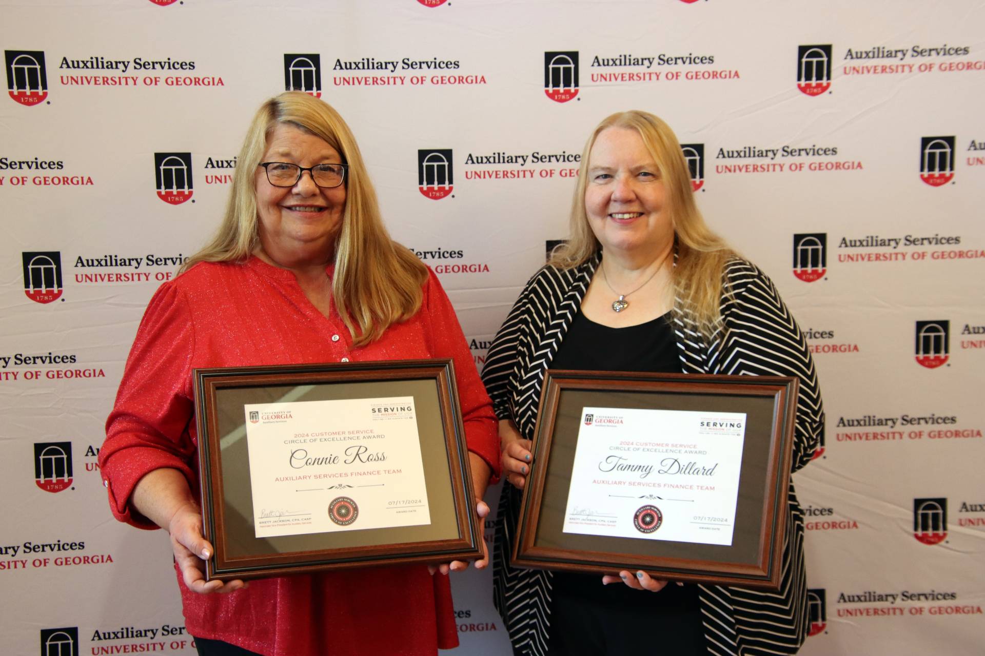 A photograph of two women holding framed certificates.