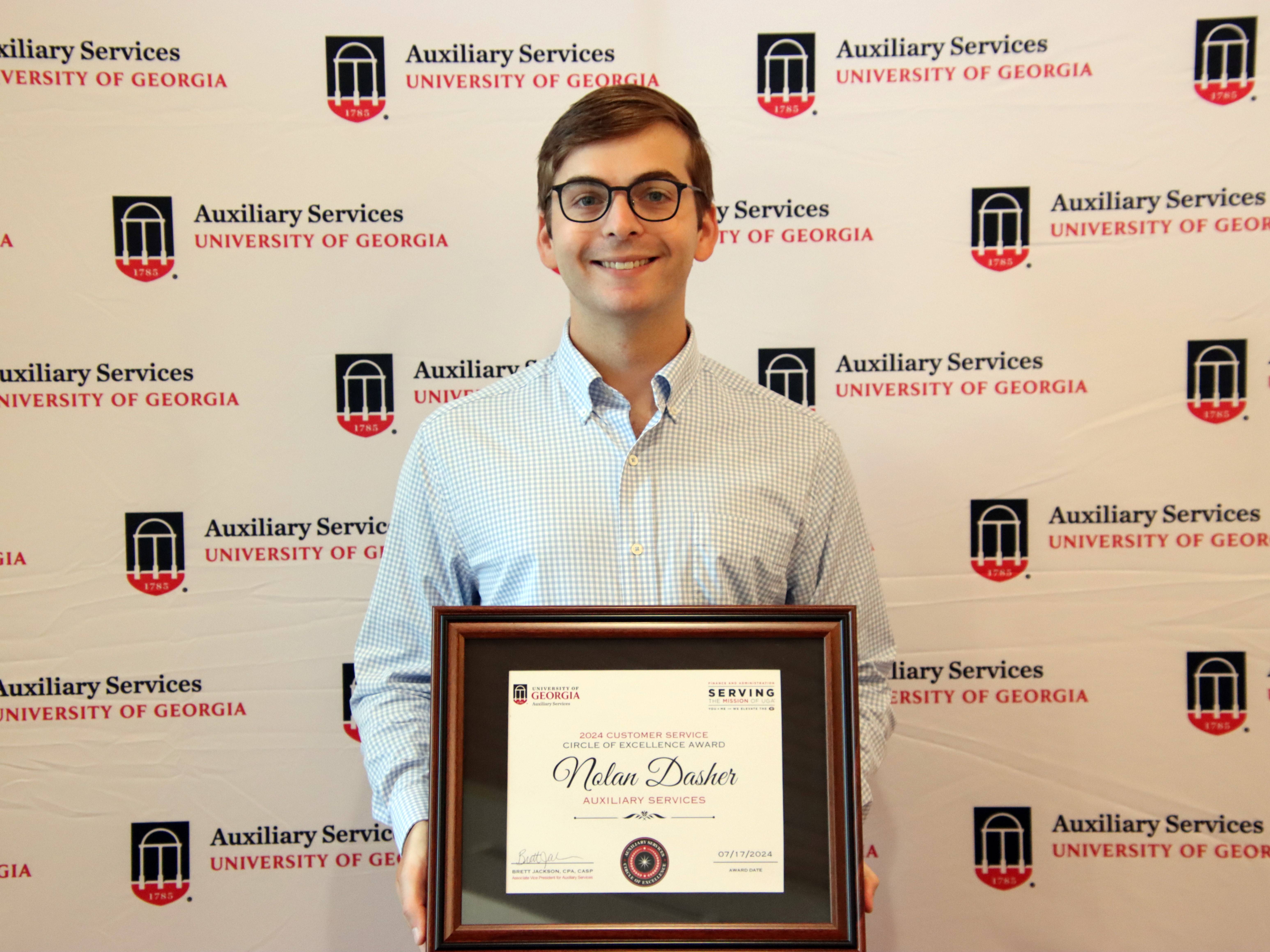 A photograph of a man holding a framed certificate.