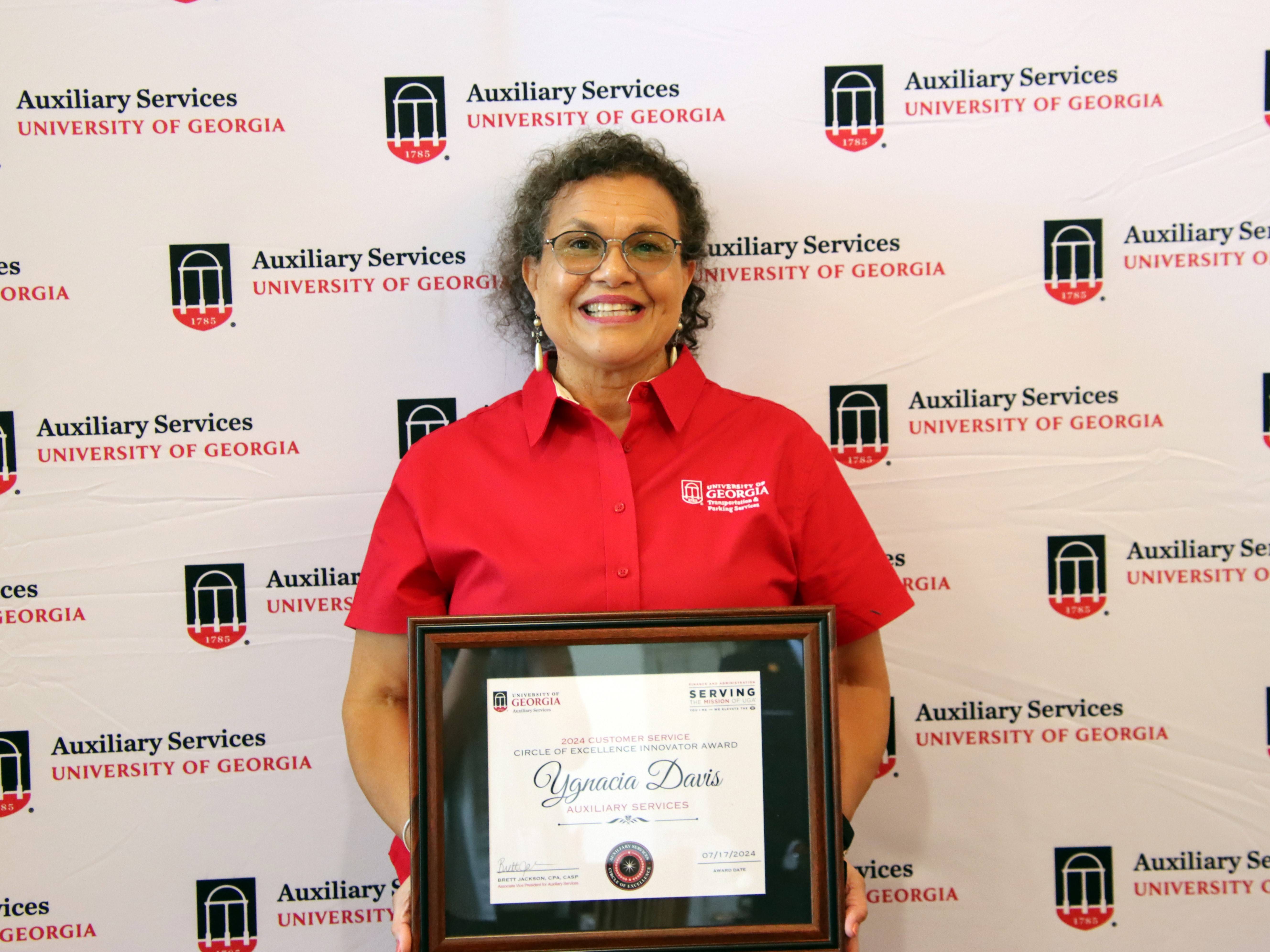 A photograph of a woman holding a framed certificate.