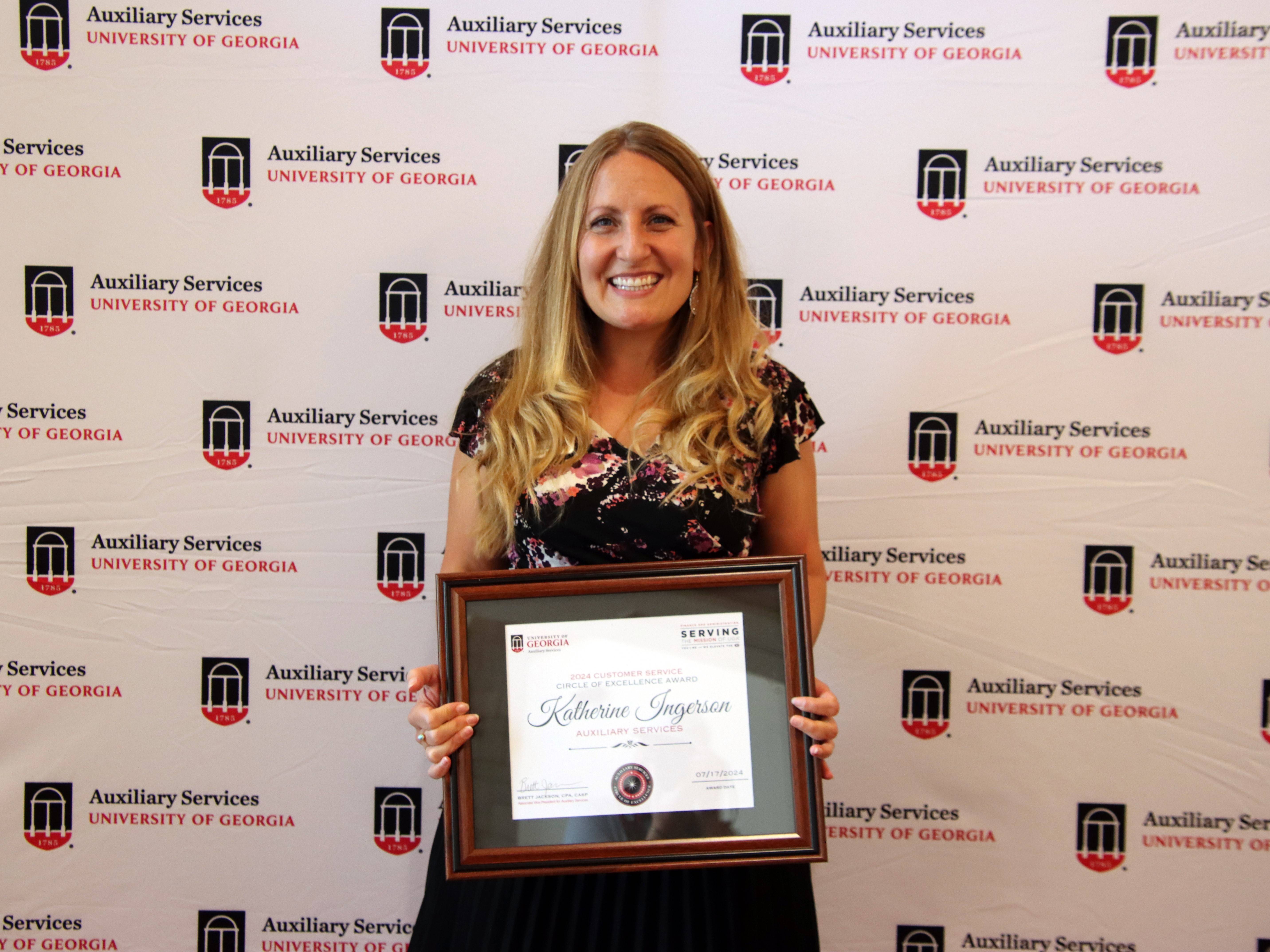 A photograph of a woman holding a framed certificate.