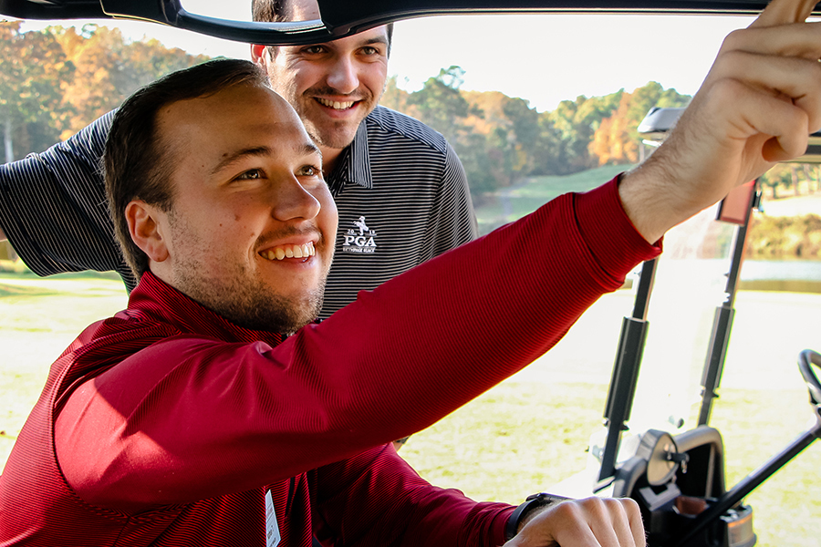 Two golf staff members working on a golf cart.