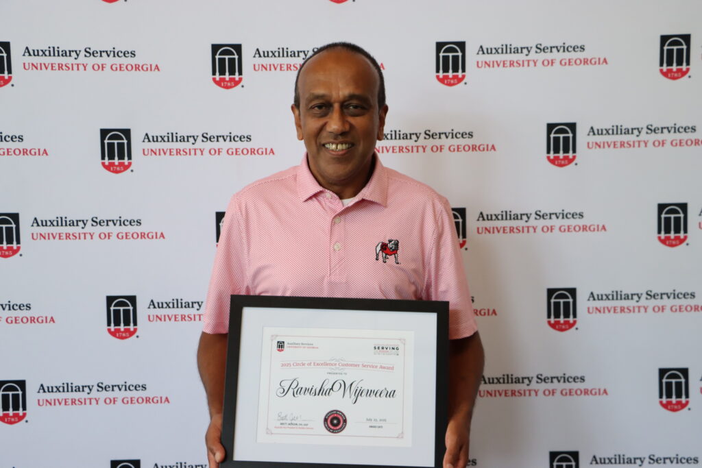 Photo of Ravisha Wijeweera holding a framed certificate