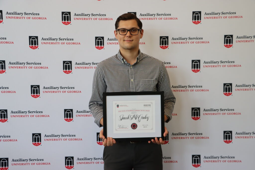 Photo of Jacob McGinley holding a framed certificate