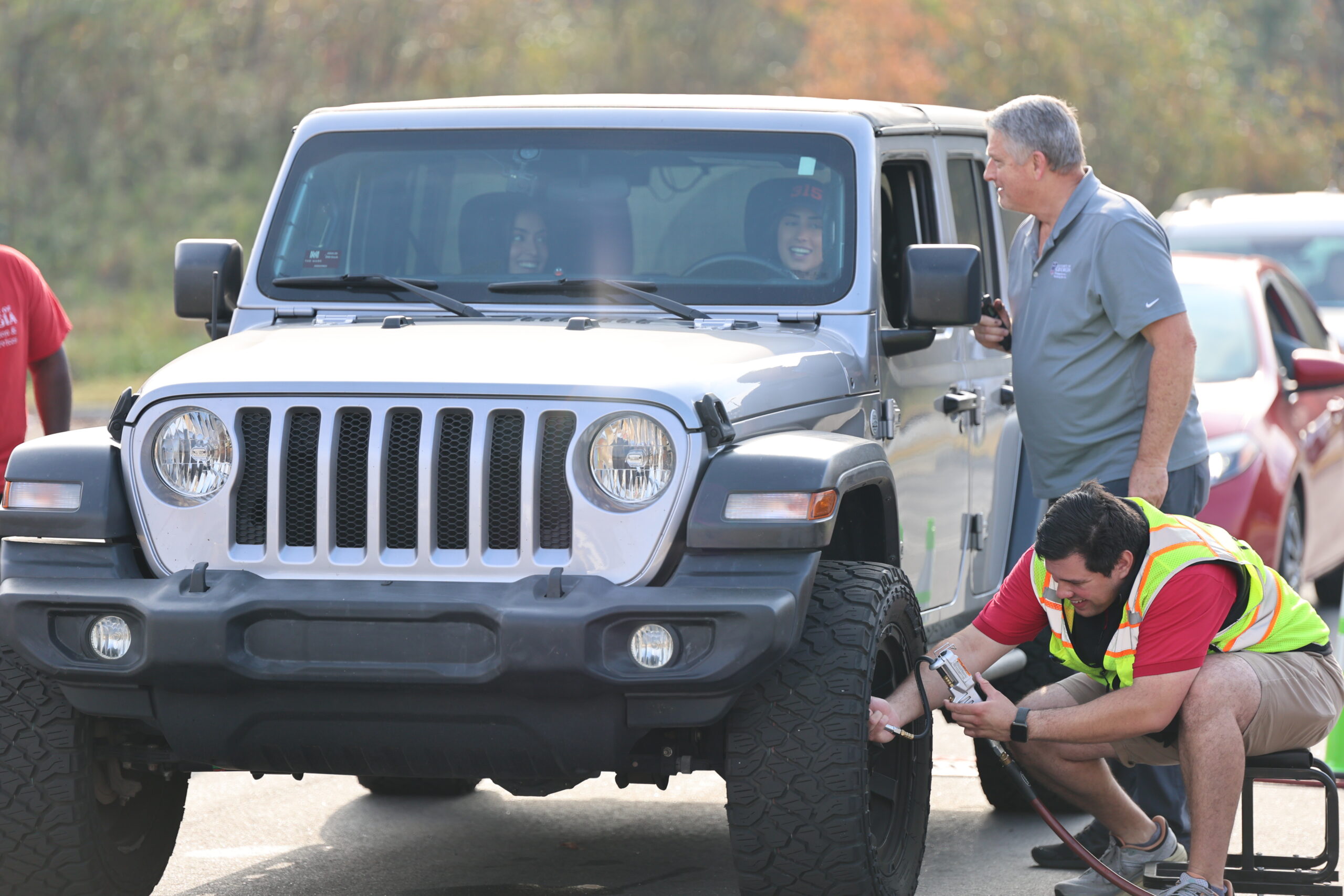A man checking the tire pressure of a Jeep