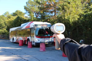 Person aiming speed tracker at bus
